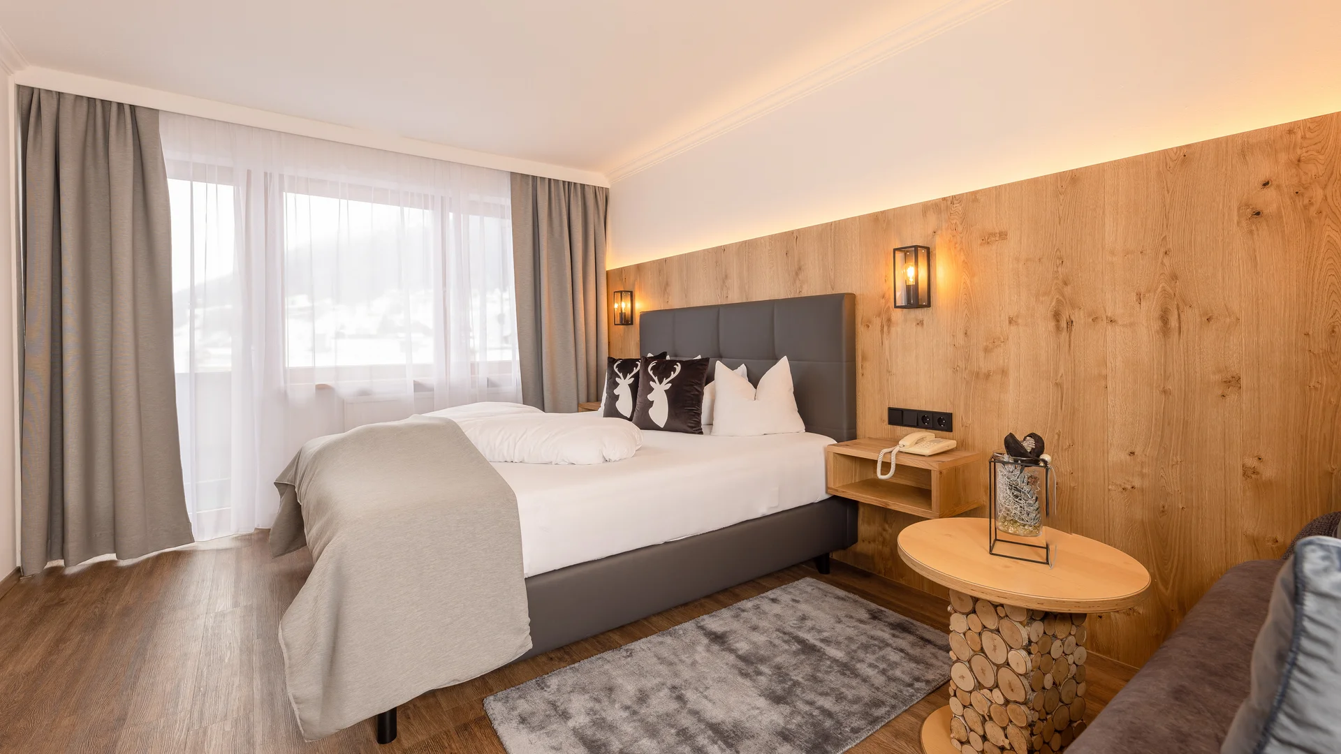 Modern bedroom with double bed, wood-paneled wall, window and round side table