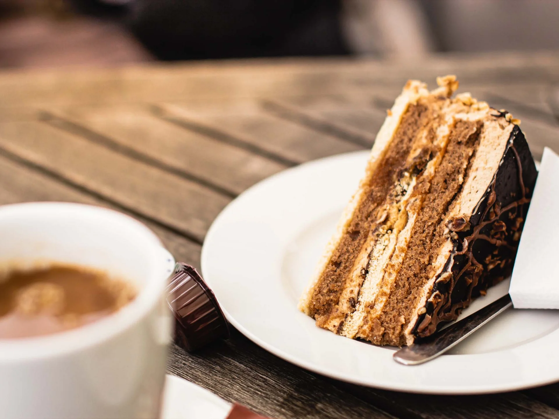 Alphof | genuine indulgence at a gourmet hotel in Tyrol Slice of chocolate cake with cream on a plate beside a cup of coffee