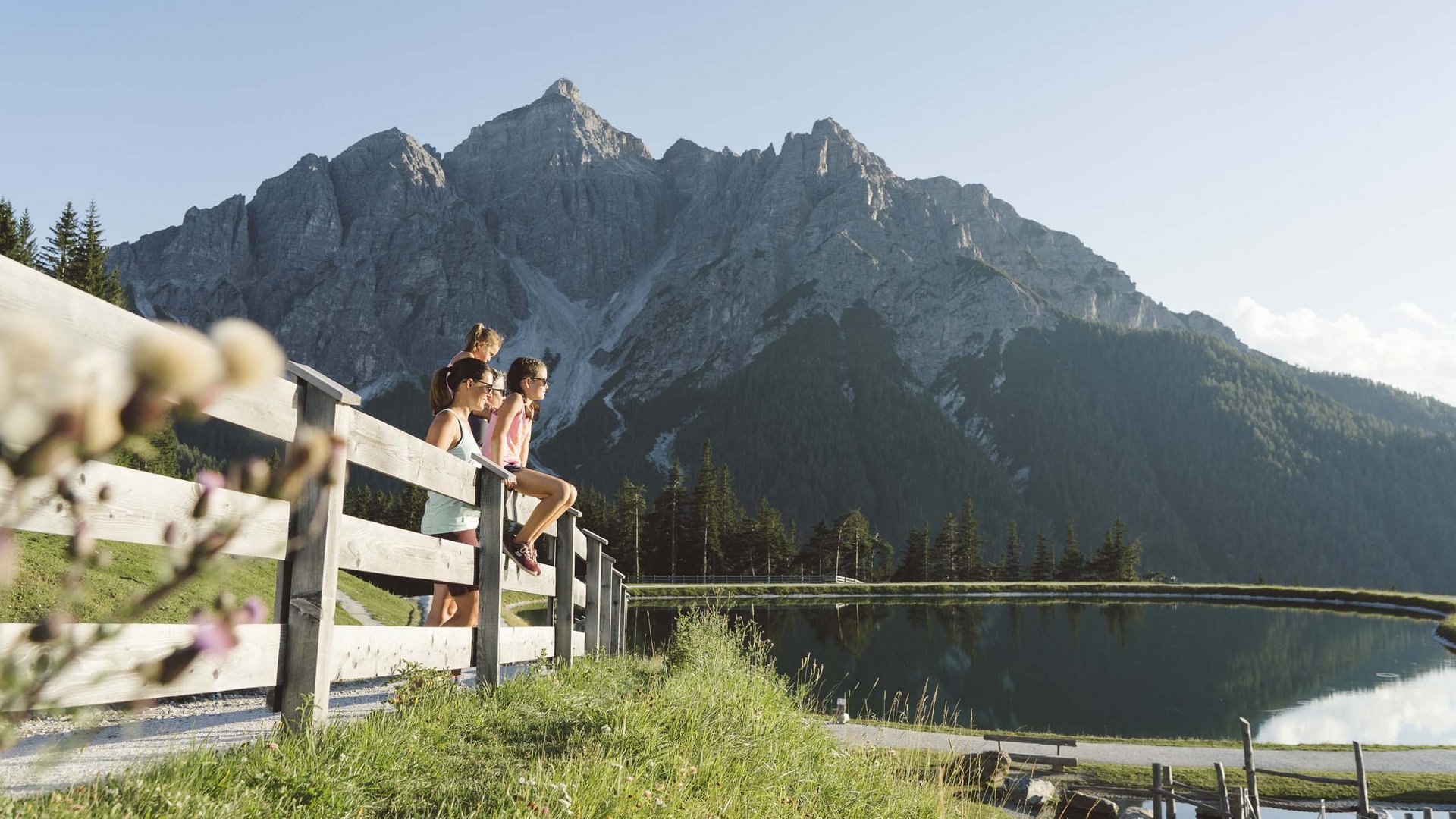 My Stubaital: a summer holiday at the Hotel Alphof Family enjoying mountain view by a peaceful lake with wooden fence in foreground