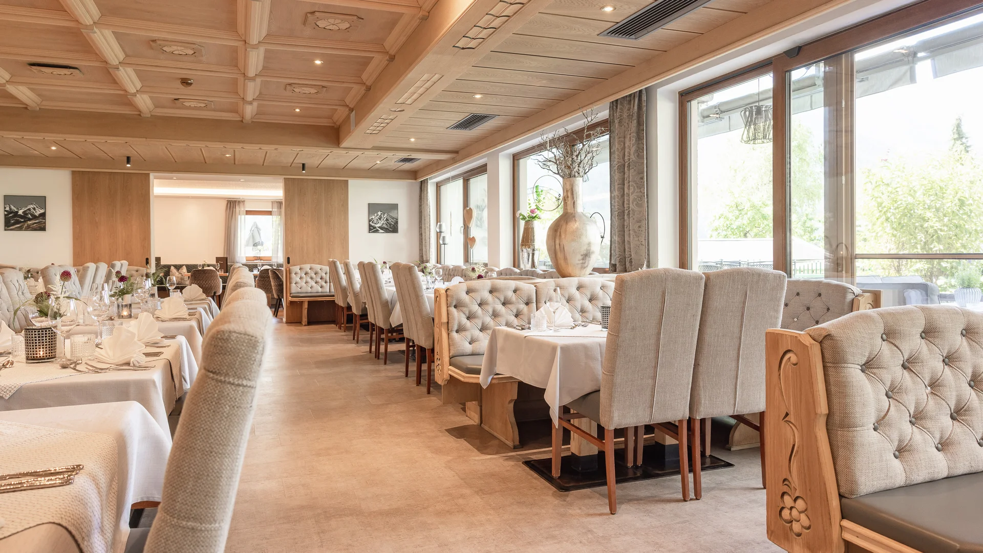 Bright dining room with set tables, upholstered chairs and large windows