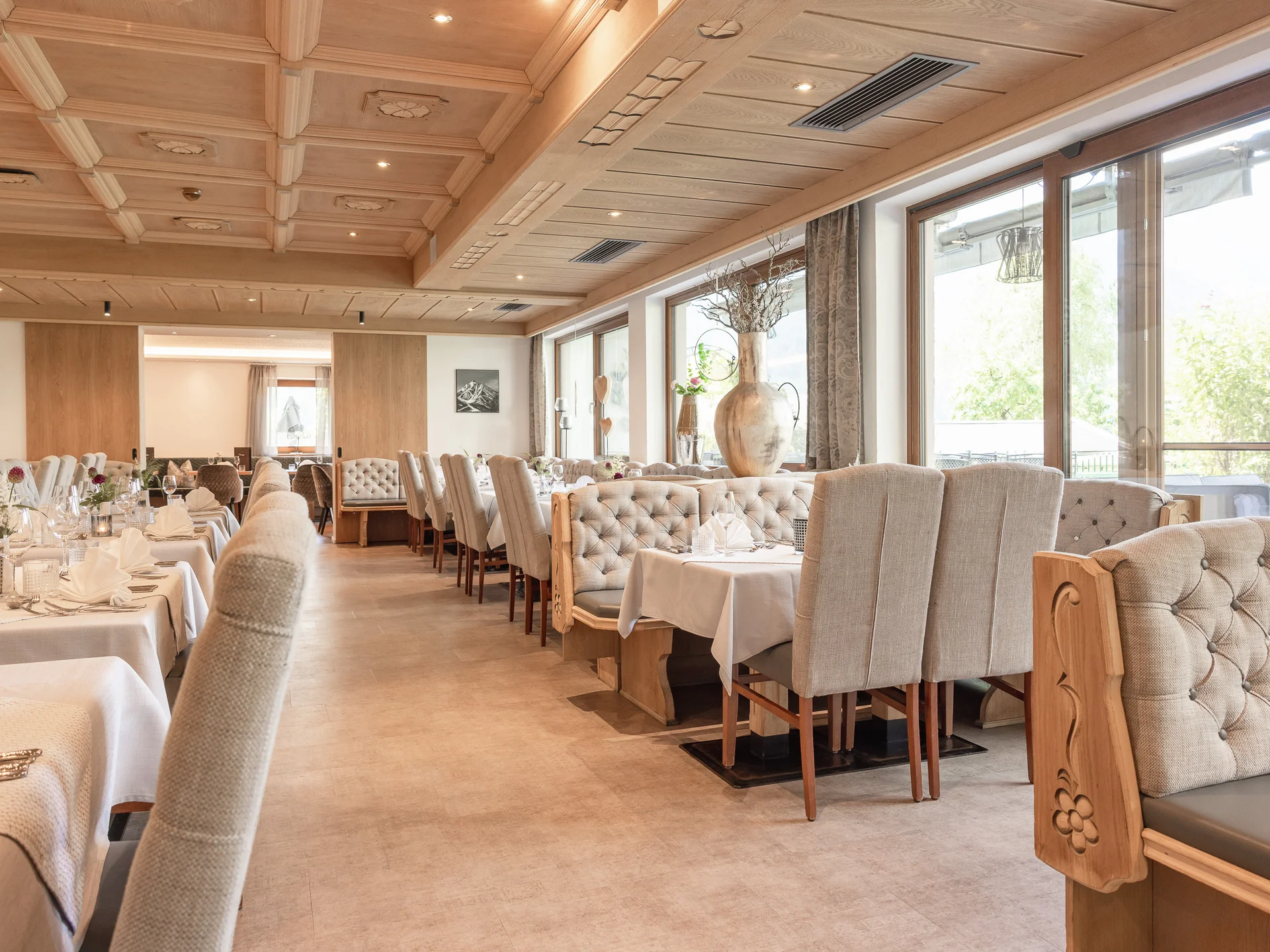 Alphof | genuine indulgence at a gourmet hotel in Tyrol Bright dining room with set tables, upholstered chairs and large windows