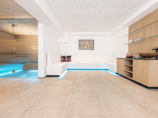 Unser Wellnesshotel im Stubaital Moderner Wellnessraum mit weißer Couch und Aromabad hinter Glastür