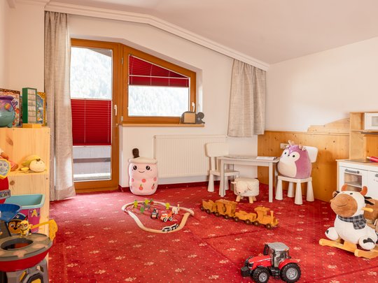 Mein Hotel in Fulpmes im Stubaital Kinderzimmer mit Spielzeug, Kuscheltieren und rotem Teppich