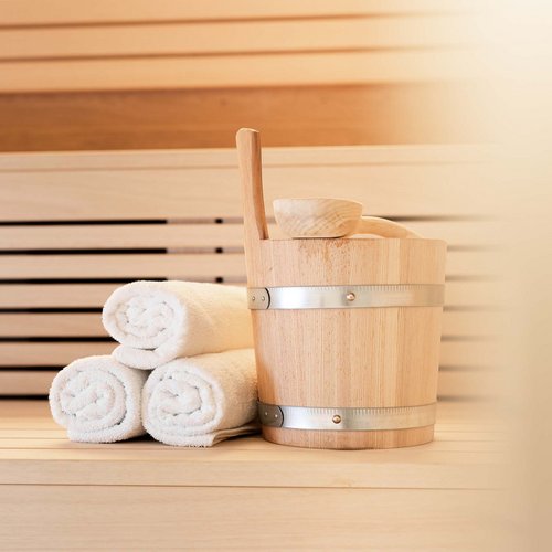 Ein feines Wellnesshotel in Fulpmes Saunazubehör mit drei weißen Handtüchern und Holzeimer auf Holzbänken