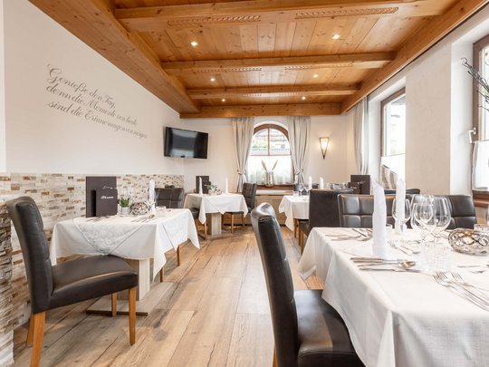 Romantik in den Bergen Gemütliches Restaurant mit Holzbalkendecke und gedeckten Tischen