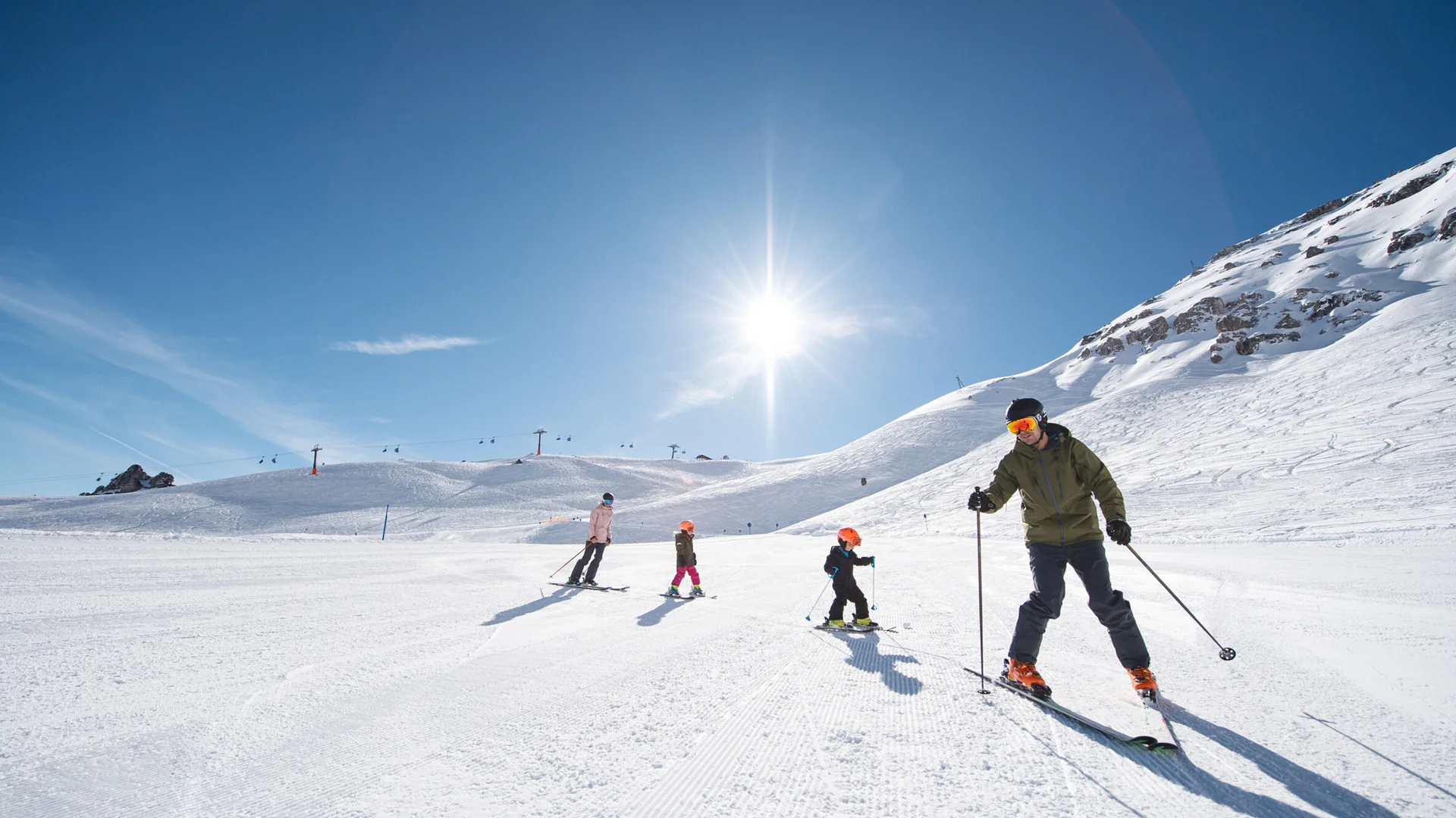 Skiers skiing down a snowy slope in bright sunshine