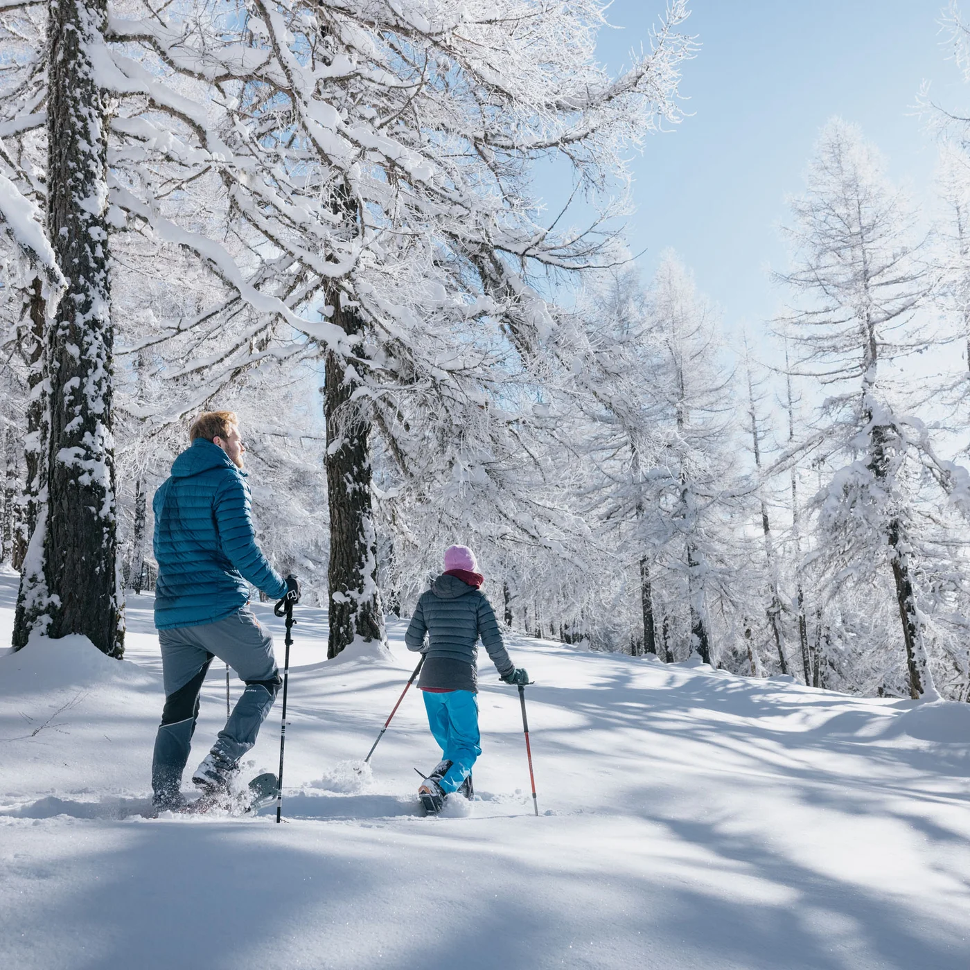 Inclusive services | Hotel Alphof in Fulpmes Two people hiking with poles through a snow-covered winter forest