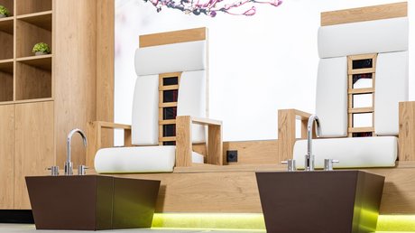 Einblicke in unser Hotel im Stubaital in Fulpmes Zwei moderne Pedikürstühle mit Fußbecken in einem Holz- und Weiß-inspirierten Spa-Raum