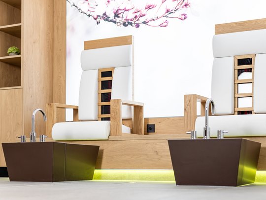 Unser Wellnesshotel im Stubaital Zwei moderne Pedikürstühle mit Fußbecken in einem Holz- und Weiß-inspirierten Spa-Raum
