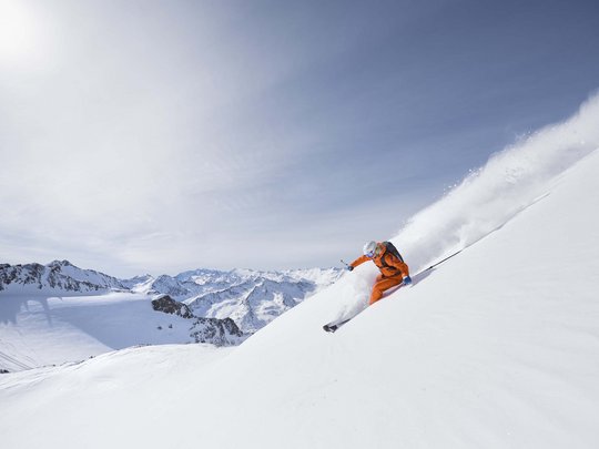 Winterurlaub in Tirol: Hotel Alphof in Fulpmes Skifahrer in orange lernt auf frischem Pulverschnee in den Alpen