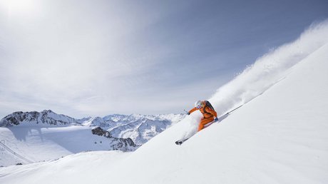 Einblicke in unser Hotel im Stubaital in Fulpmes Skifahrer in orange lernt auf frischem Pulverschnee in den Alpen