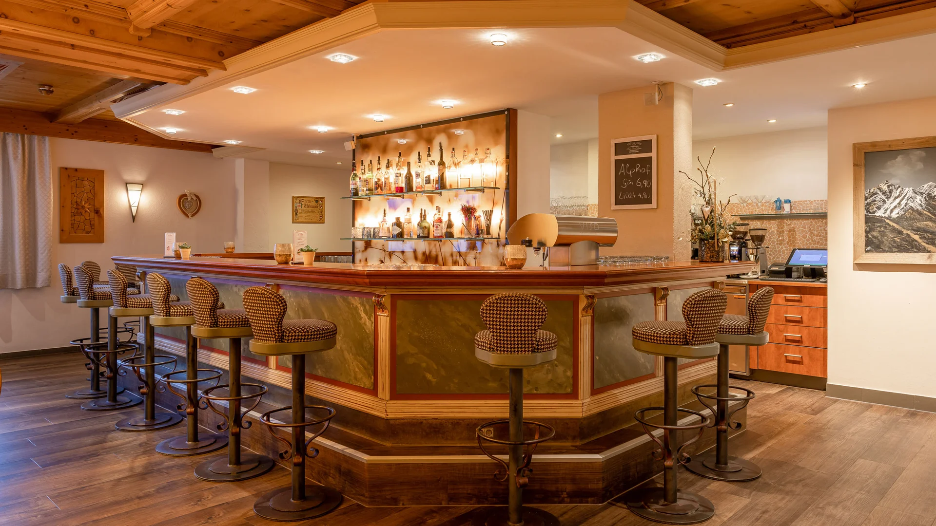 Rustic hotel bar with wooden ceiling, bottle shelves and upholstered bar stools