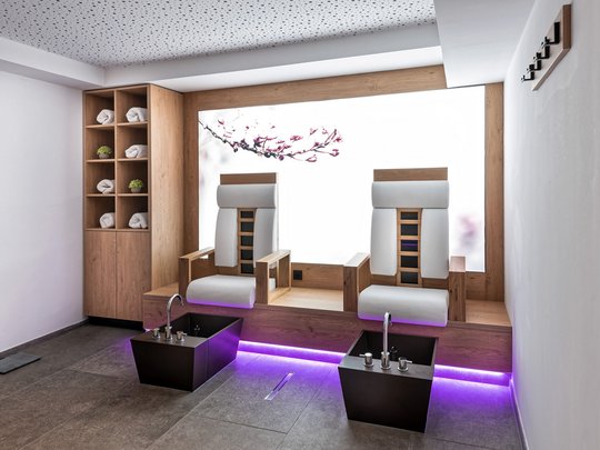 Ein feines Wellnesshotel in Fulpmes Moderner Spa-Bereich mit zwei Pediküre-Stühlen und Fußbecken