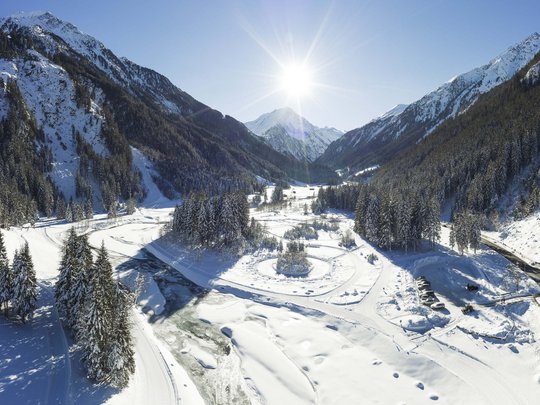 Winterurlaub in Tirol: Hotel Alphof in Fulpmes Sonnige Winterlandschaft mit schneebedeckten Bergen und gefrorenem Fluss