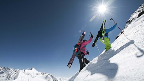 Einblicke in unser Hotel im Stubaital in Fulpmes Zwei Skifahrer steigen bei Sonne und klarem Himmel einen steilen, schneebedeckten Hang hinauf