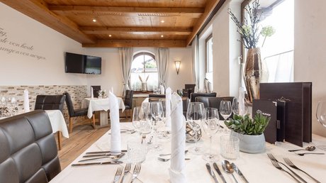Einblicke in unser Hotel im Stubaital in Fulpmes Geschmackvoll gedeckter Tisch in einem gemütlichen Restaurant mit Holzbalkendecke
