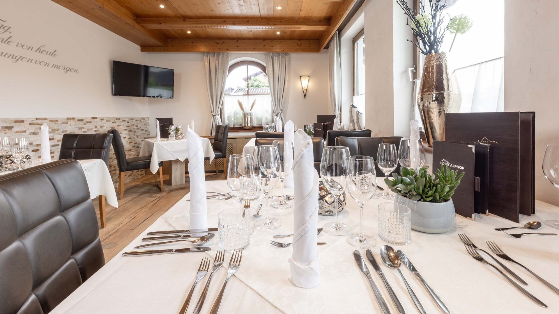 Hotel Alphof: ein Gourmethotel in Tirol Geschmackvoll gedeckter Tisch in einem gemütlichen Restaurant mit Holzbalkendecke