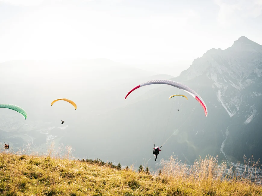 Several paragliders flying over a misty mountain landscape