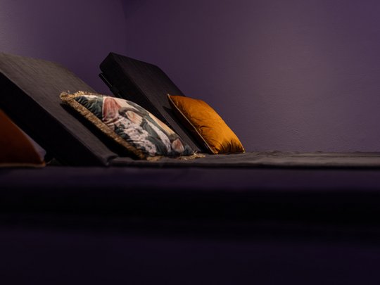 Ein feines Wellnesshotel in Fulpmes Dunkle Relaxliegen mit bunten Kissen vor violetter Wand