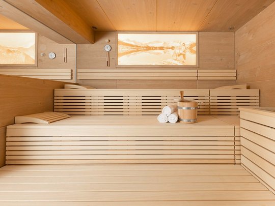 Unser Wellnesshotel im Stubaital Moderne Sauna mit Holzverkleidung, Bänken, Handtüchern und Holzeimer