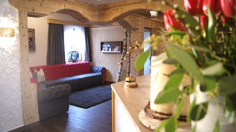 An inside look at our hotel in Stubaital in Fulpmes Cozy hotel lobby with red sofa, wooden accents, and a floral arrangement