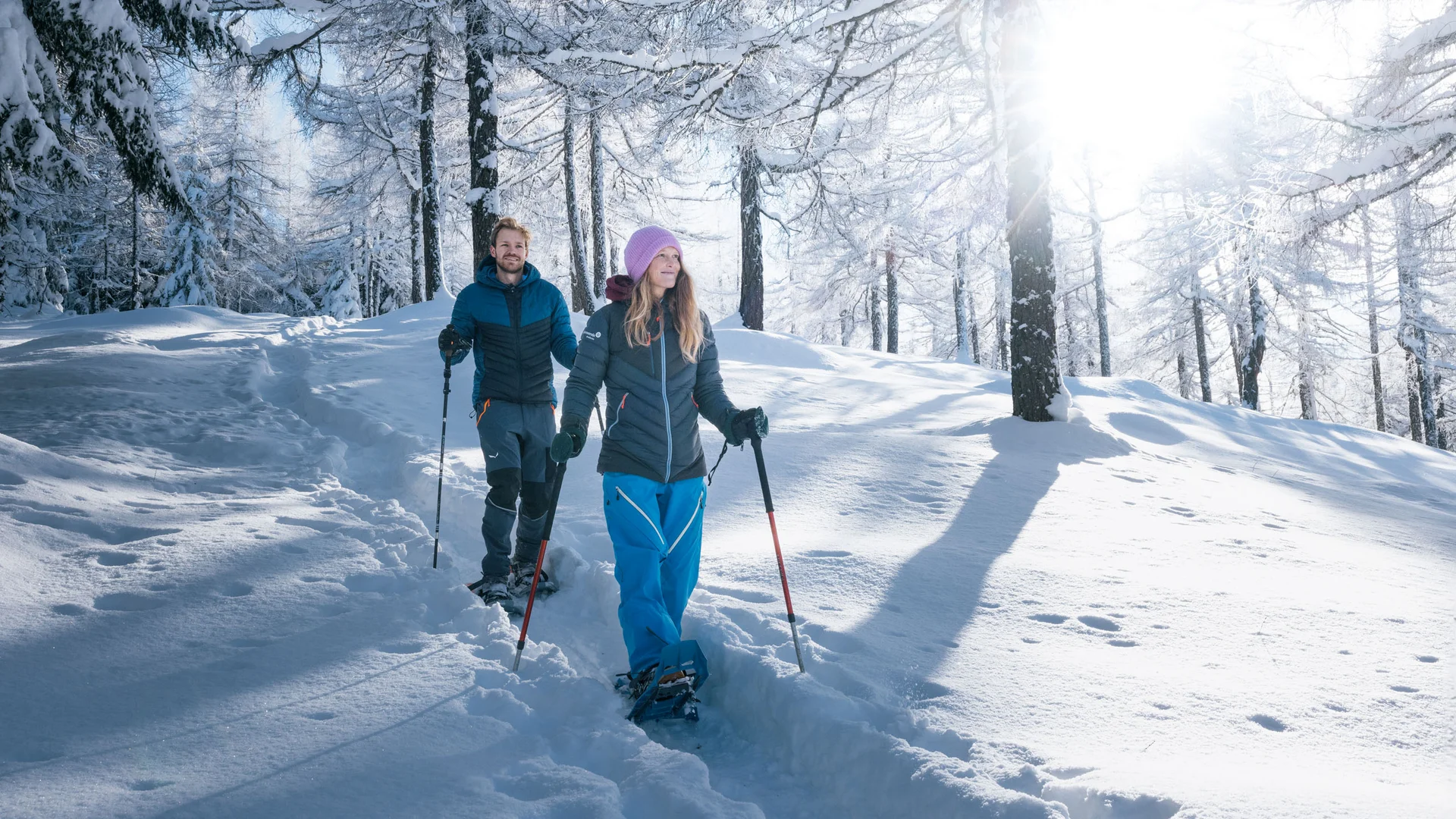 Two snowshoers walking through a snow-covered forest