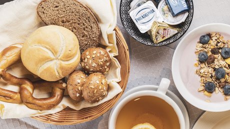 Einblicke in unser Hotel im Stubaital in Fulpmes Frühstück mit Brötchen, Brezeln, Butter, Müsli mit Beeren und Tee mit Zitrone