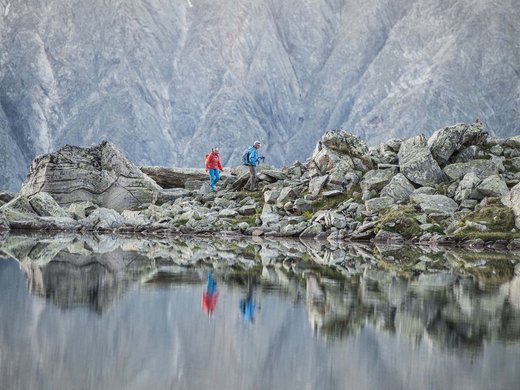 My Stubaital: a summer holiday at the Hotel Alphof Hikers on rocky trail with mountain lake and reflection in water