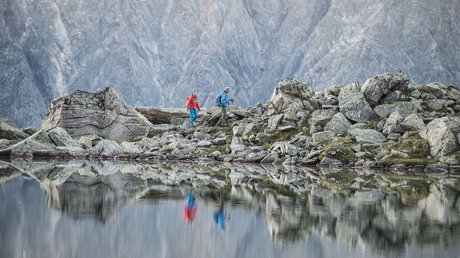Einblicke in unser Hotel im Stubaital in Fulpmes Wanderer auf felsigem Weg mit Bergsee und Spiegelung im Wasser
