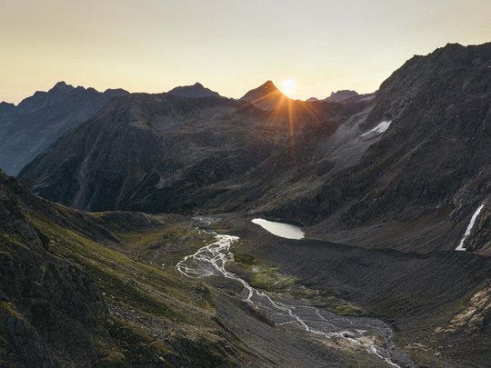 Sommerurlaub im Stubaital: nicht ohne meine Stubai Super Card Sonnenaufgang über Bergtal mit kleinem See und Fluss in den Alpen