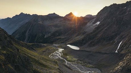 Einblicke in unser Hotel im Stubaital in Fulpmes Sonnenaufgang über Bergtal mit kleinem See und Fluss in den Alpen