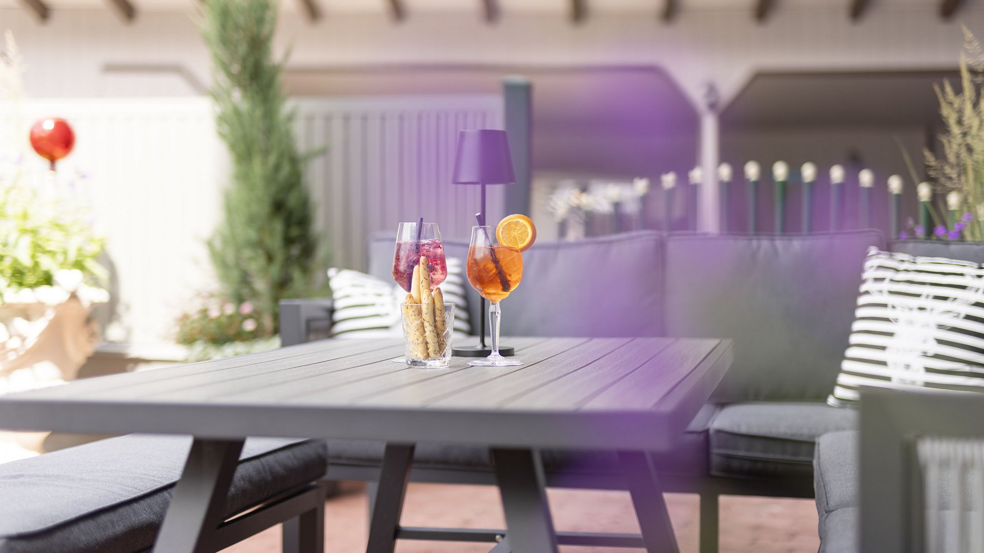 Hotel Alphof: ein Gourmethotel in Tirol Getränke und Snacks auf grauem Gartentisch mit Sitzgelegenheiten im Hintergrund