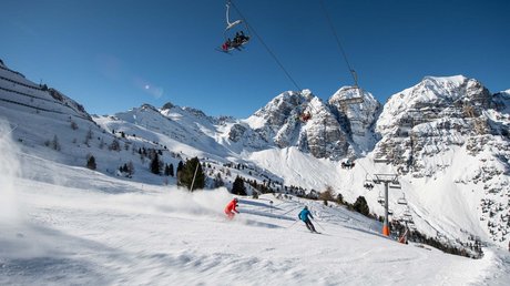 Einblicke in unser Hotel im Stubaital in Fulpmes Skifahrer auf verschneiter Piste mit Sessellift und Bergen bei klarem Himmel