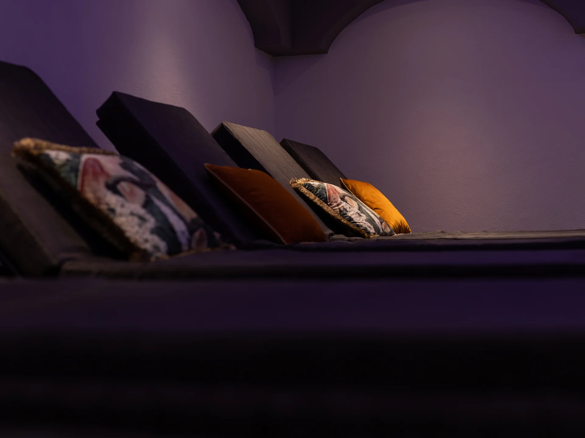 The modern AlpSpa at your spa hotel in Tyrol Dark seating or lounging area with colorful cushions against a purple-lit wall