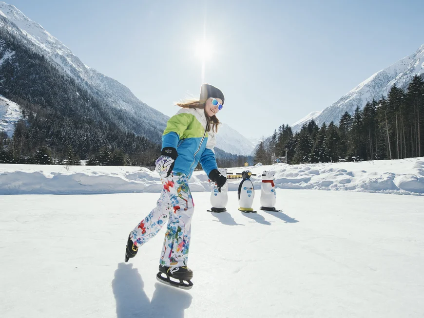 Ice skater in front of snowy mountains and three curling stones