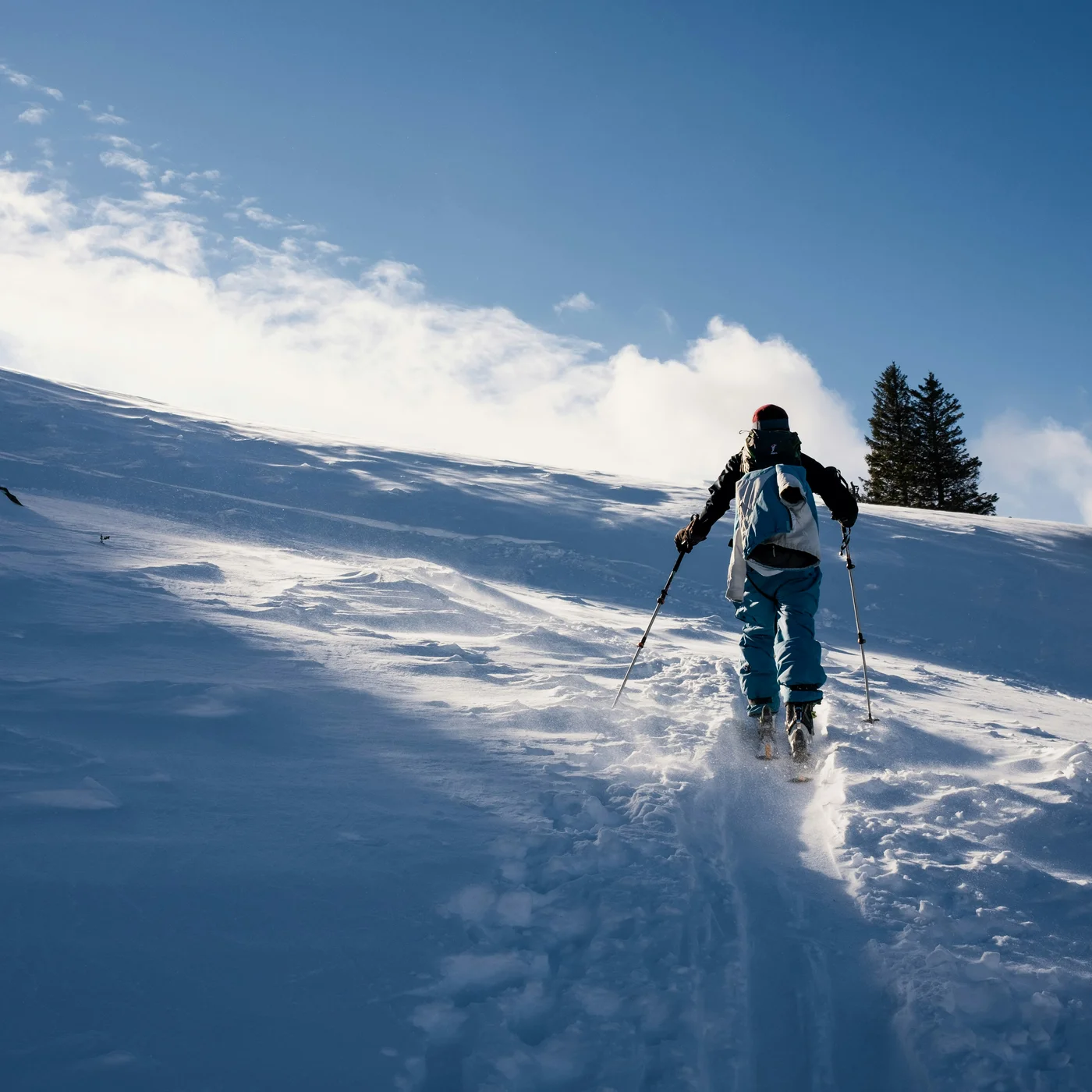 Skier climbing a snowy slope with poles