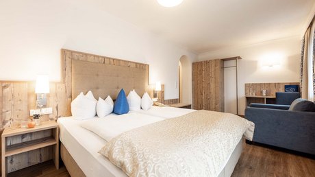 Einblicke in unser Hotel im Stubaital in Fulpmes Helles Hotelzimmer mit Doppelbett, Holzakzenten und Sitzbereich