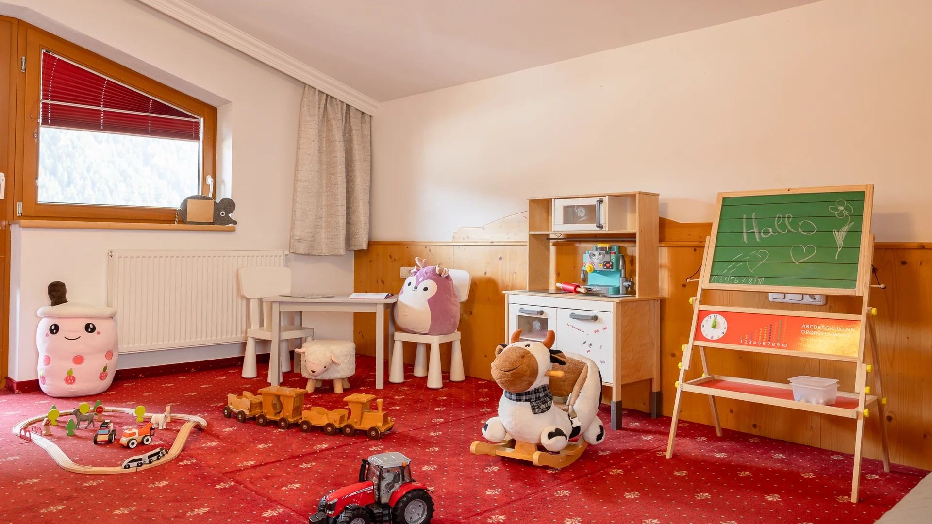 Children’s playroom with toys, rocking horse, play kitchen and chalkboard