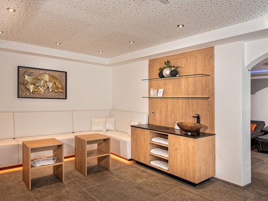 Ein feines Wellnesshotel in Fulpmes Modern eingerichteter Wartebereich mit weißem Ecksofa und Holzregal