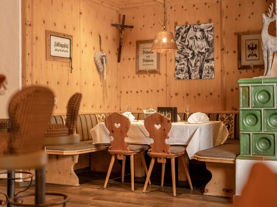 Ein feines Wellnesshotel in Fulpmes Gemütliche Holz-Eckbank mit Tischen, Stühlen und Alpen-Dekoration im Restaurant