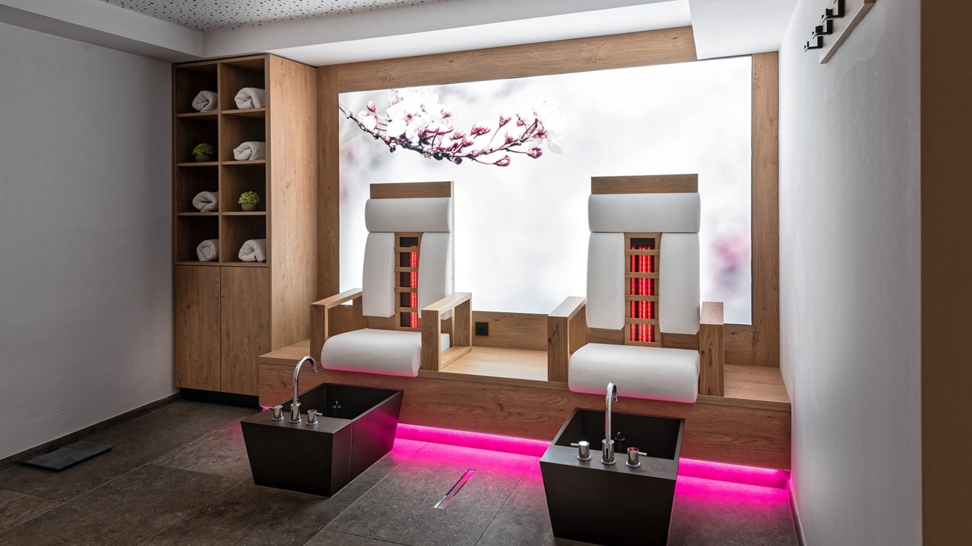 Family hotel in Austria: experience Tyrol at Alphof Modern pedicure station with two chairs, foot basins, and pink lighting