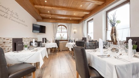 Einblicke in unser Hotel im Stubaital in Fulpmes Elegantes Restaurant mit weißen Tischdecken und braunen Lederstühlen