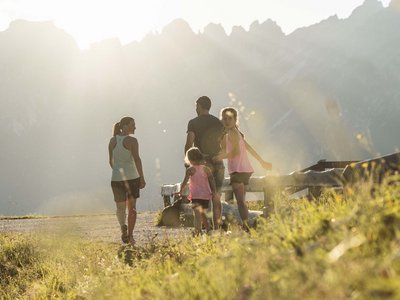 Skipiste oder Sommerrodelbahn? Stubai bietet von allem etwas! Familie wandert auf einem sonnigen Bergweg mit Blick auf die Berggipfel