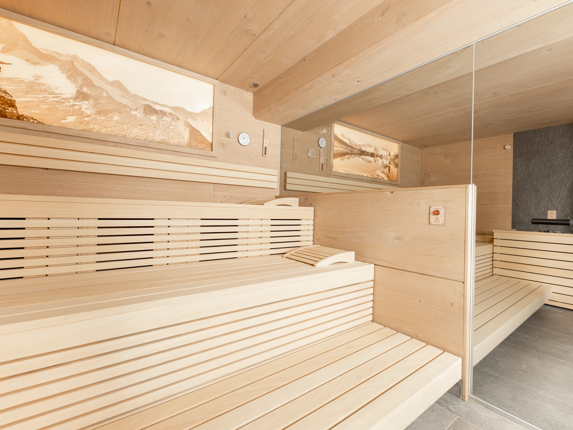 The modern AlpSpa at your spa hotel in Tyrol Bright wood sauna with benches, mirrored wall and mountain pictures