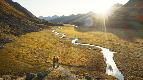 Einblicke in unser Hotel im Stubaital in Fulpmes Zwei Wanderer stehen auf einem Felsen und blicken auf einen sonnigen Fluss im Tal
