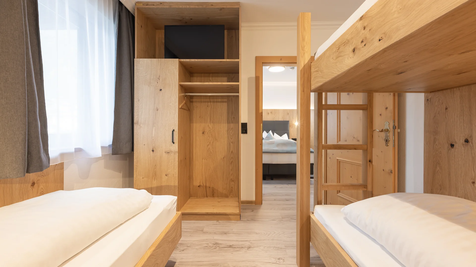 Bright room with two single beds, wooden bunk bed and open wardrobe