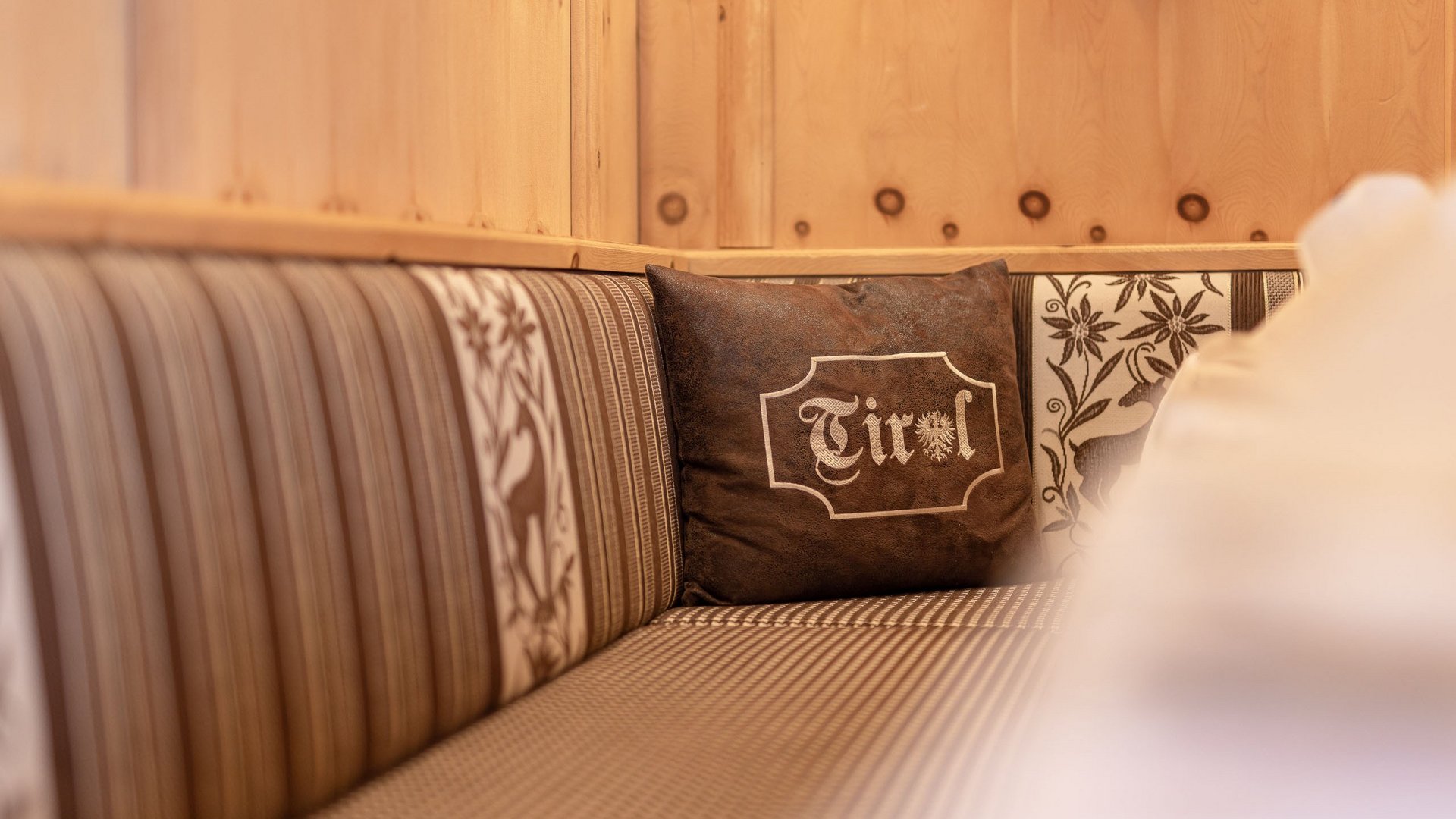 Family hotel in Austria: experience Tyrol at Alphof Cozy corner bench with wooden paneling and Tirol pillow