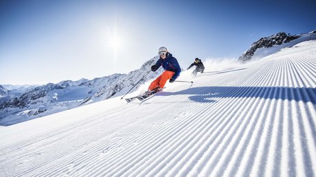 Einblicke in unser Hotel im Stubaital in Fulpmes Zwei Skifahrer fahren auf frisch präparierter Piste bei sonnigem Wetter