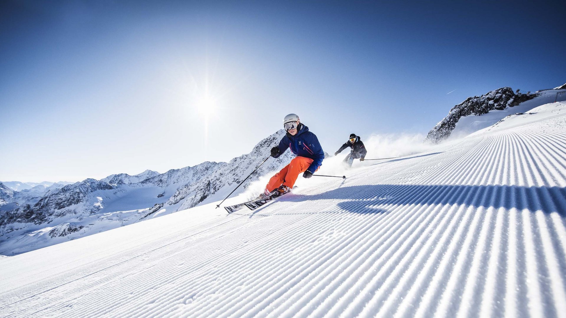 Winterurlaub in Tirol: Hotel Alphof in Fulpmes Zwei Skifahrer fahren auf frisch präparierter Piste bei sonnigem Wetter