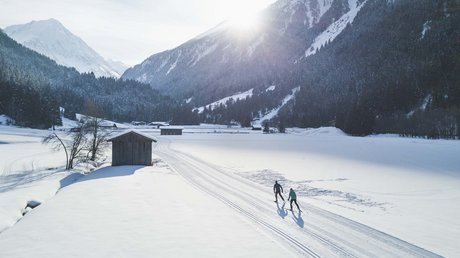 Einblicke in unser Hotel im Stubaital in Fulpmes Zwei Langläufer auf verschneiter Strecke vor Bergen im Sonnenschein